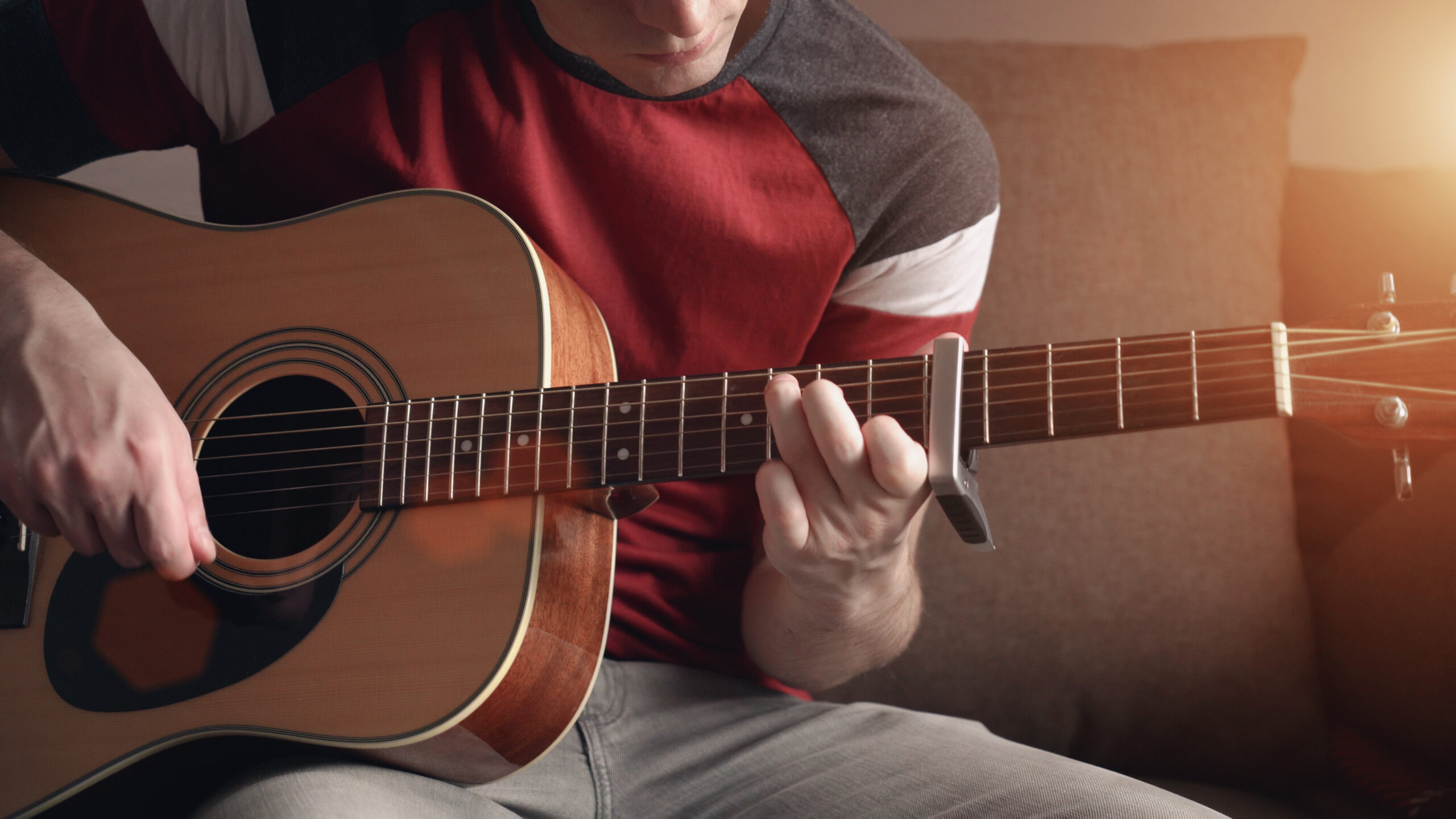 Młody mężczyzna uczy się grać na gitarze akustycznej